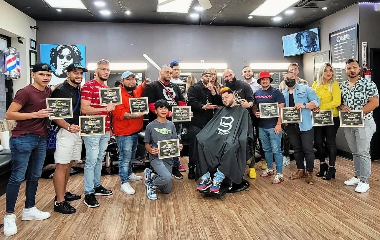 Students holding their training certificates with Tulpi The Barber and Drastic The Barber in Greenville.