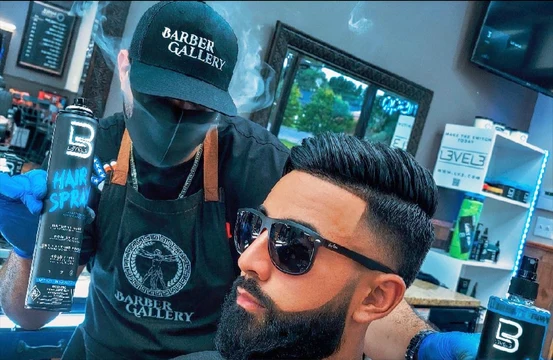 Tulpi wearing a Barber Gallery cap presents L3VEL3 products beside a model with a finished hairstyle and beard.