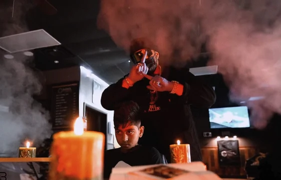 A filming scene with two people, candles and smoke in the barbershop.
