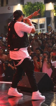 An artist with a microphone facing the audience on stage.