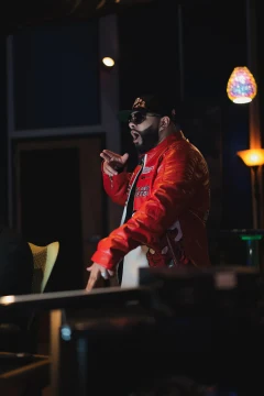 An artist wearing a red jacket during a studio recording.