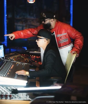Two professionals coordinating a recording beside a console.