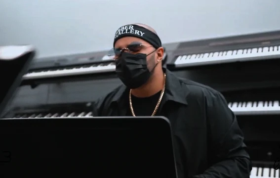 An artist sitting beside a piano during filming.