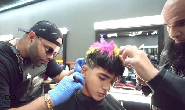 A barber detailing a colorful haircut beside another professional.