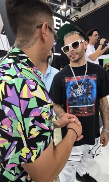 Two men greeting each other at an event; one wears an El Portal T-shirt.